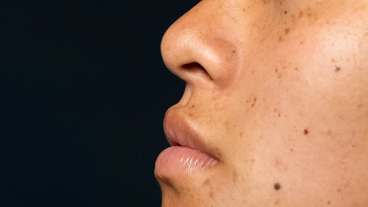 A woman applying skincare products to her face, targeting hyperpigmentation for a radiant complexion.