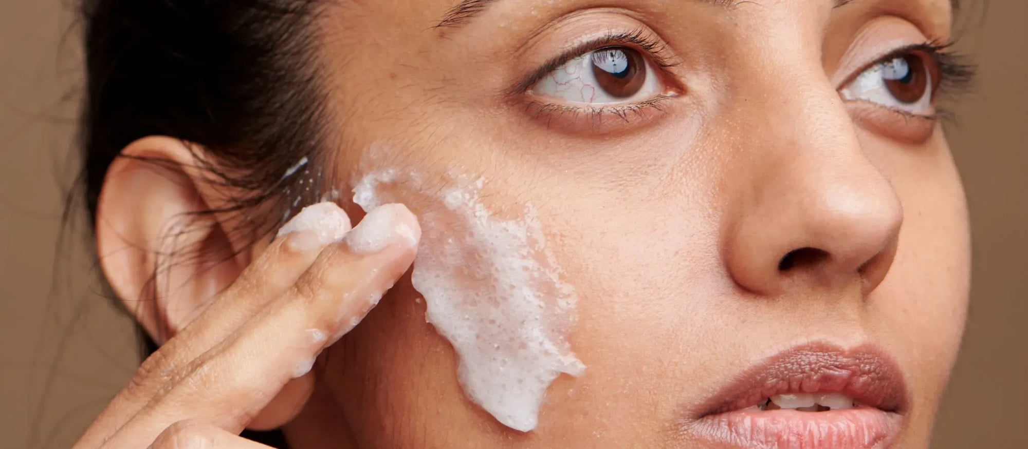 A person applying SPF 50 sunscreen on their face, highlighting daily sun protection benefits.