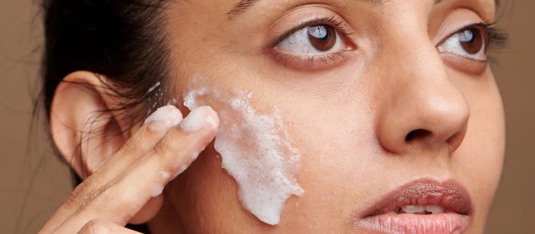 A person applying SPF 50 sunscreen on their face, highlighting daily sun protection benefits.