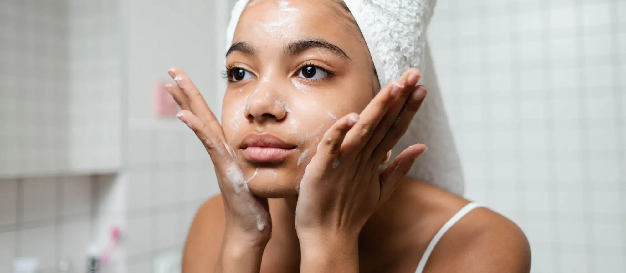 A person demonstrating effective face washing techniques for clearer skin in a well-lit bathroom.