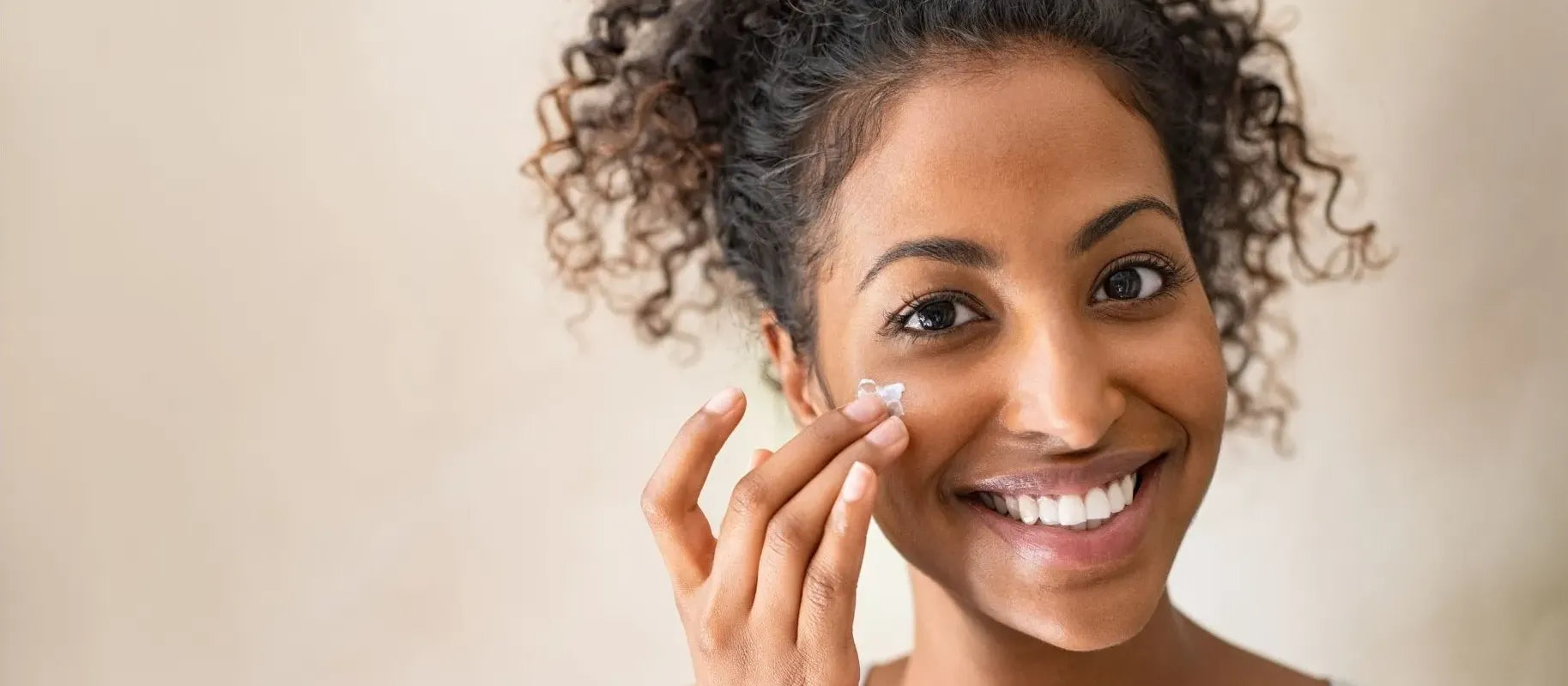A woman applying sunscreen on her face, demonstrating effective sunscreen application for flawless skin.