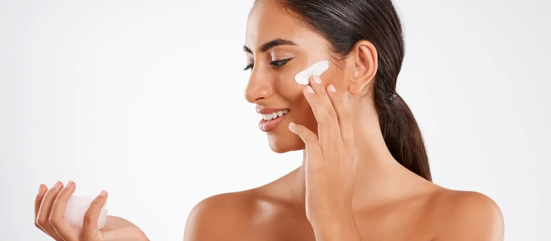 A bottle of body sunscreen designed for sensitive skin placed on a beach towel with a sunny background.