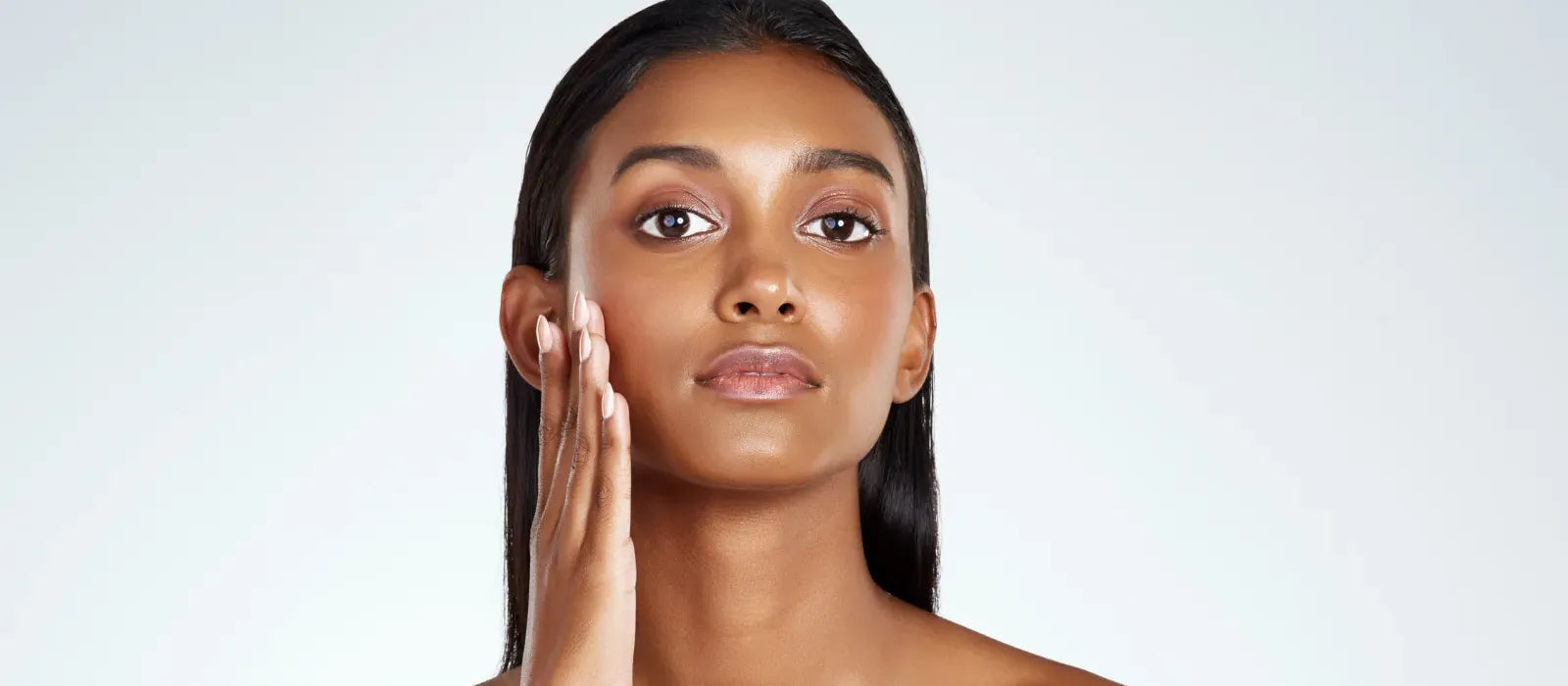 A woman applying sunscreen designed for combination skin in a sunny outdoor setting.
