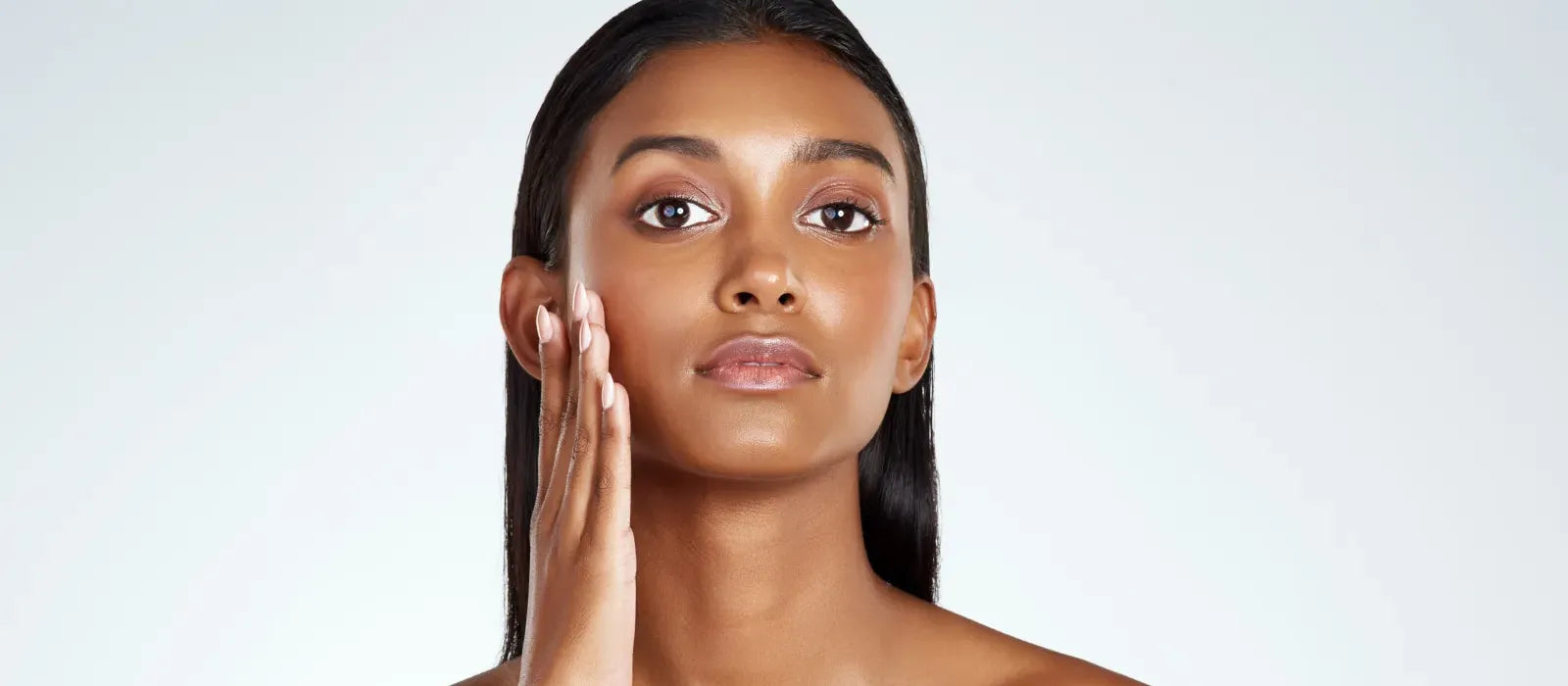A woman applying sunscreen on her pigmented skin outdoors, highlighting essential sun protection tips.