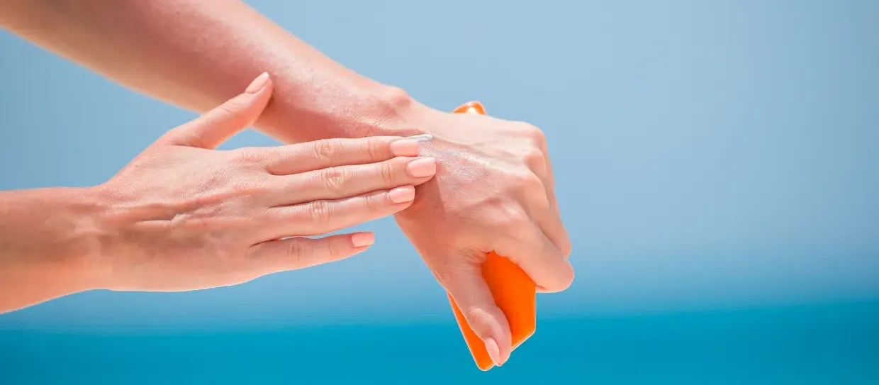A woman applying sunscreen to her face, focusing on melasma and hyperpigmentation protection.