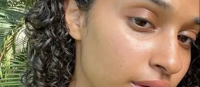 A woman applying tinted sunscreen on pigmented skin, showcasing a natural glow and sun protection.