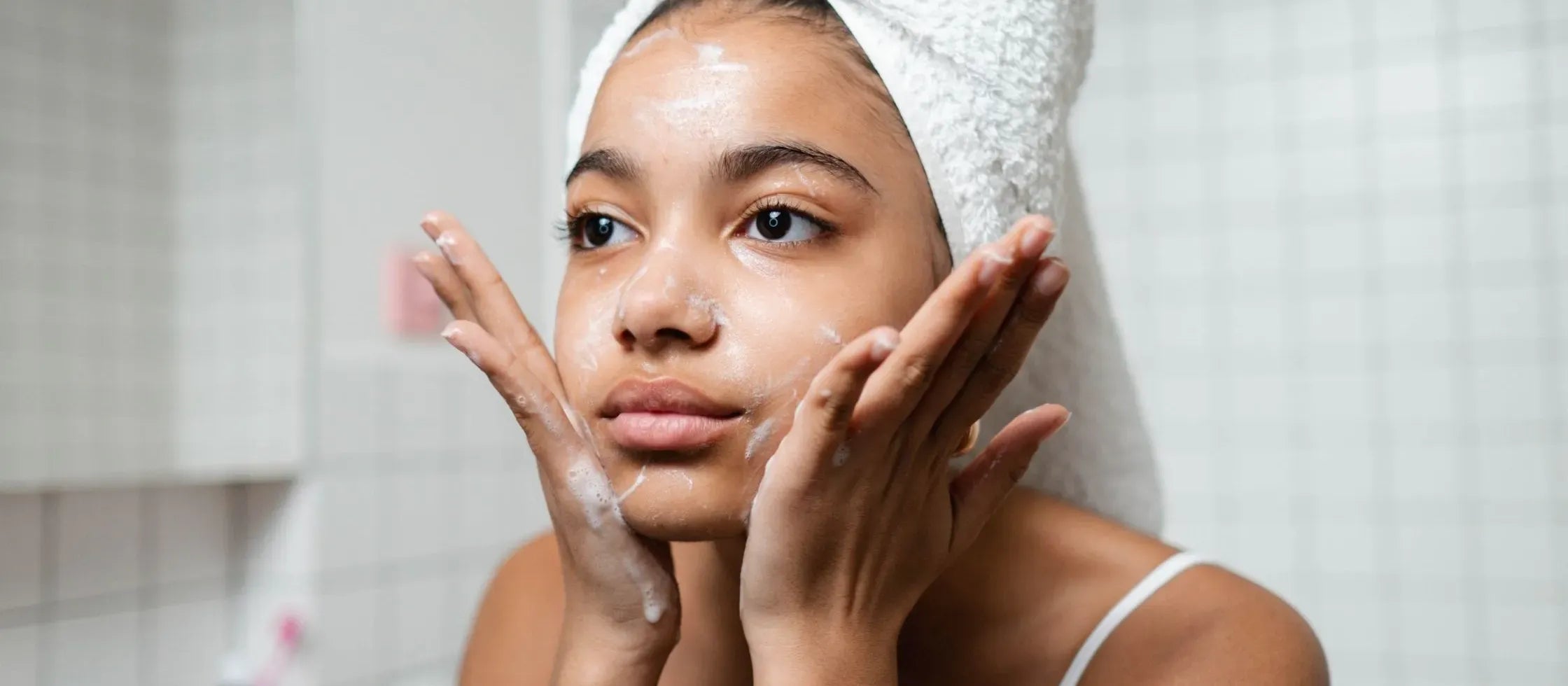 A person selecting the best acne clearing face wash from a variety of skincare products on a shelf.