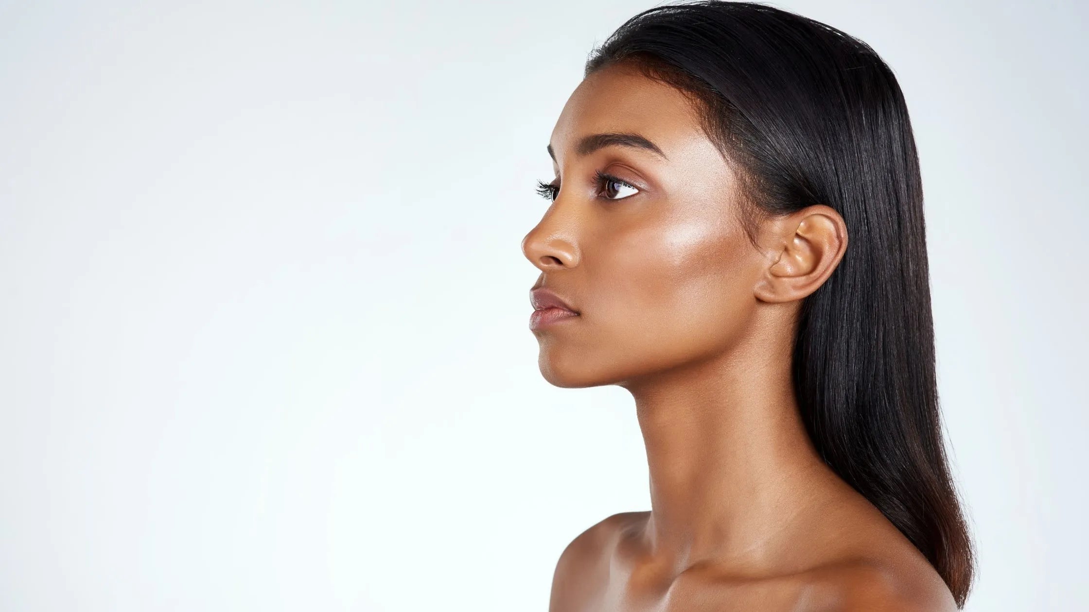 A bottle of SPF 50 sunscreen designed for oily skin, placed on a beach towel with sunglasses and a sunhat.