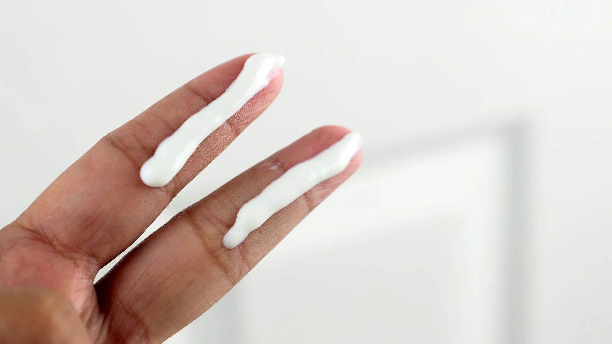 A woman applying waterproof sunscreen on her face before heading outdoors on a sunny day.