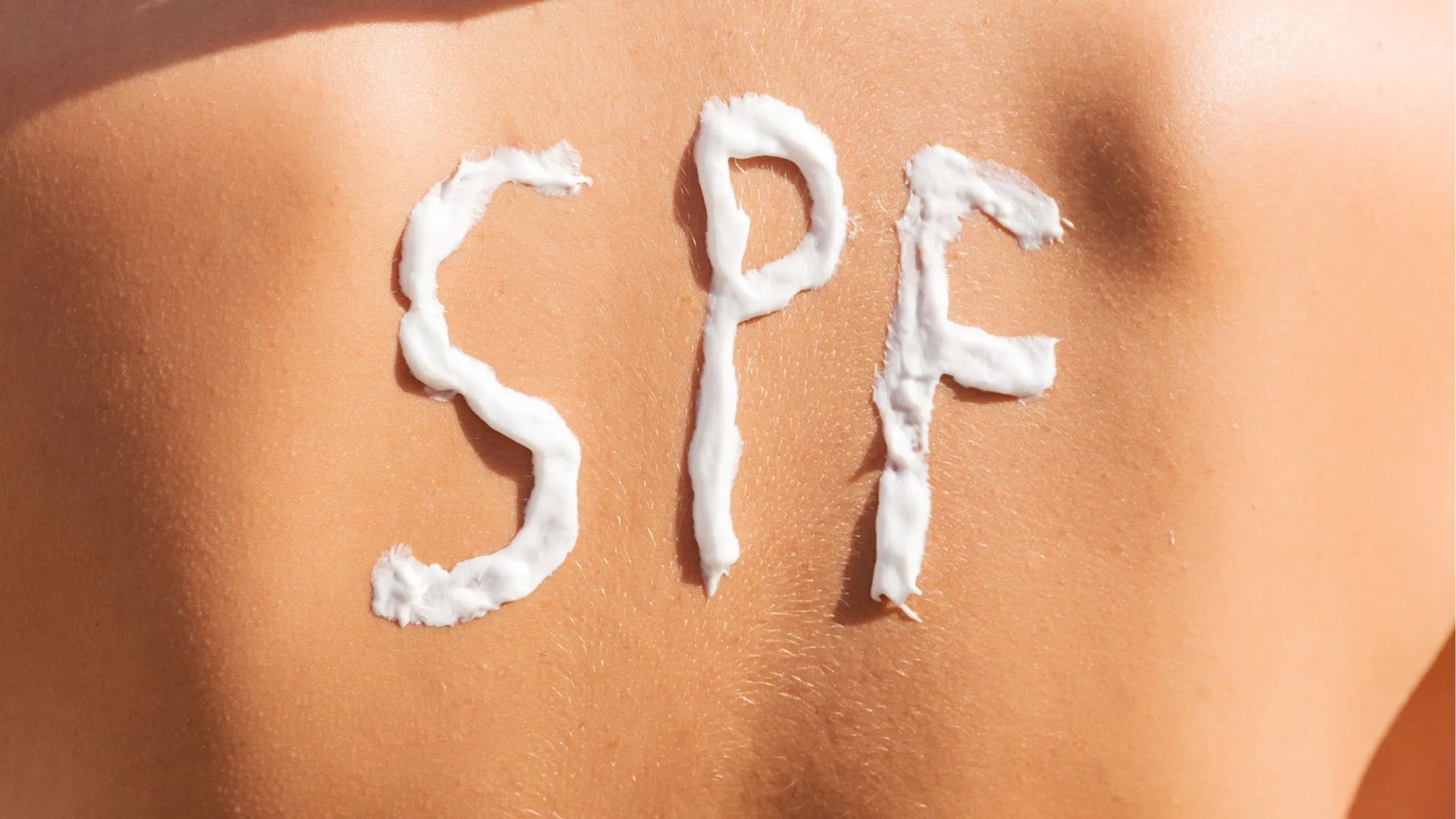 A bottle of SPF 50 sunscreen lotion for body care on a beach towel, emphasizing sun protection and skincare.
