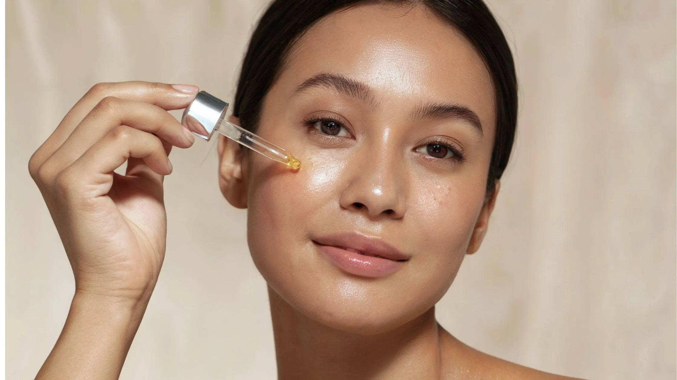 A woman applying an acne serum to her face, showcasing radiant skin and the benefits of skincare products.