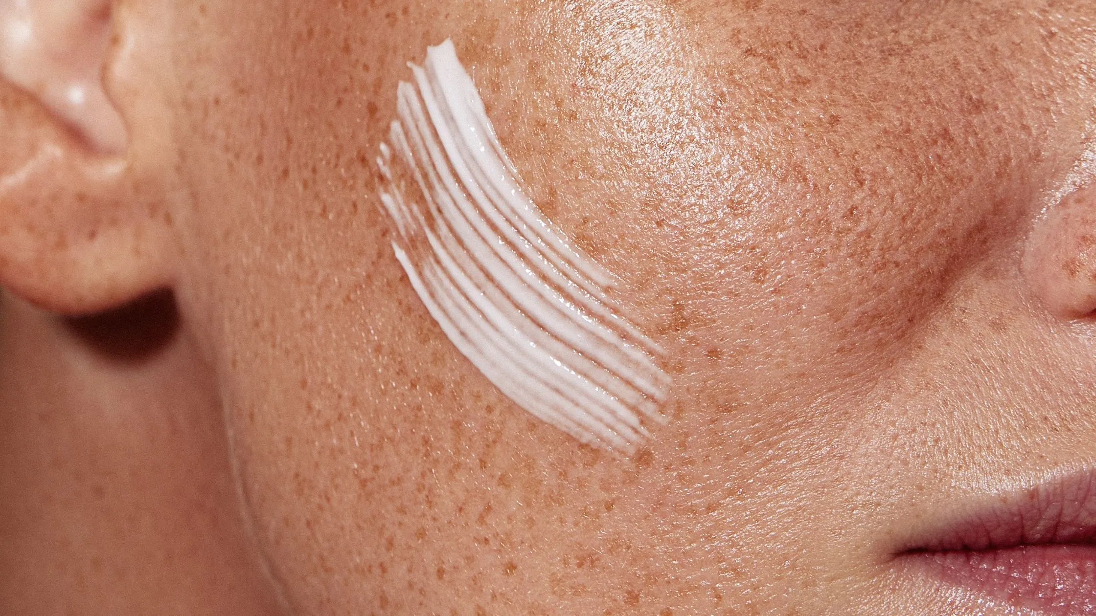 A bottle of sunscreen for normal skin placed on a sunlit beach, highlighting its essential protective qualities.