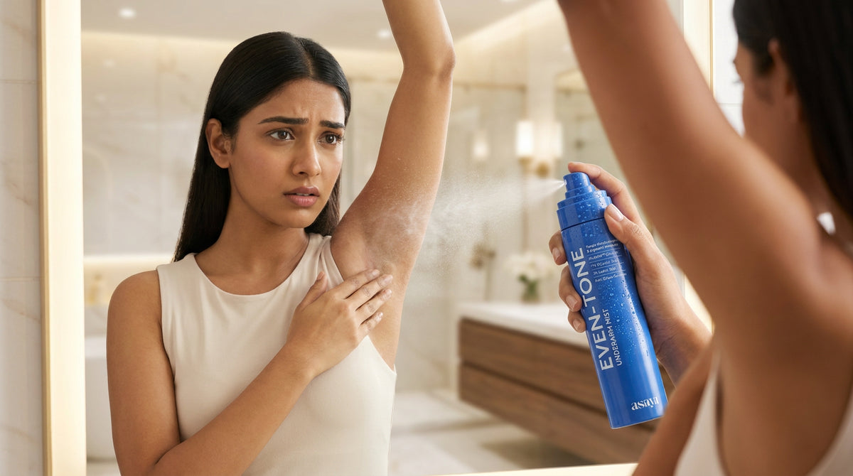A young Indian woman wearing a sleeveless top looks concerned while noticing dark, uneven underarm pigmentation in front of a mirror. She applies the Even Tone Underarm Mist  